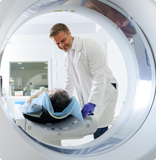 A male doctor preparing a patient for a scan inside a GE Optima CT machine.